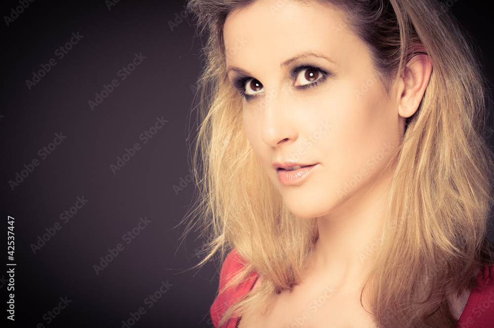 Naklejka premium Young adult woman smiling against dark background