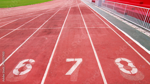 Lanes of a red race track with numbers and red seats in the stad