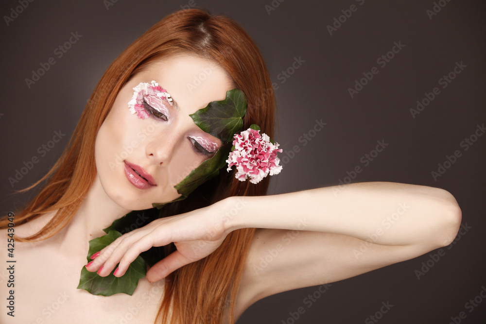 Portrait of red-haired girl with flower and make-up.