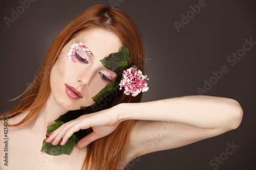 Portrait of red-haired girl with flower and make-up.