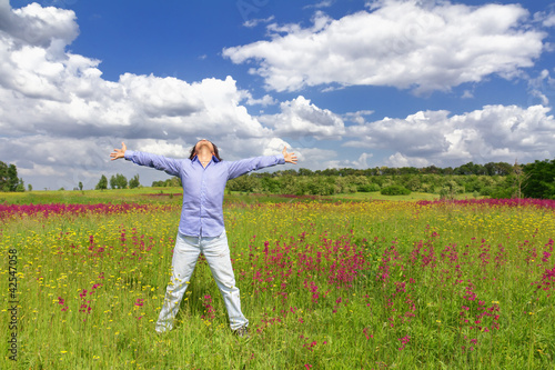Young man standing on a meadow on a blue sky background