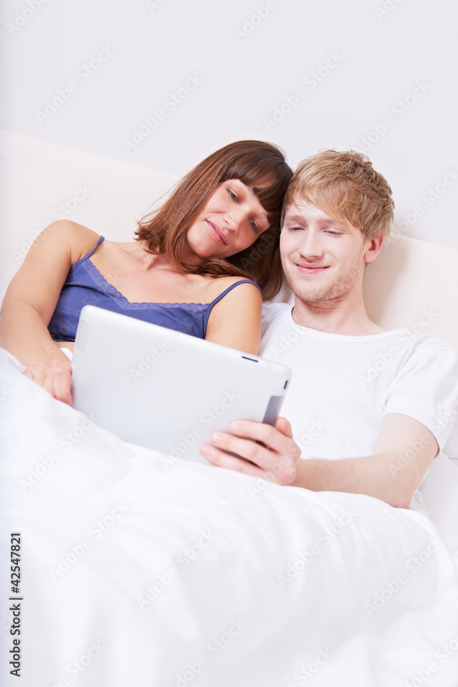 Paar schaut Videos im Bett auf Tablet Computer Paar schaut Videos im Bett auf Tablet Computer