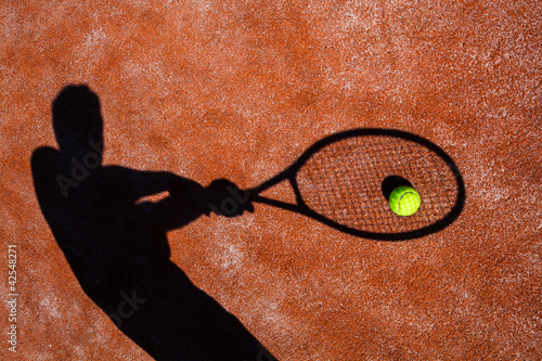 shadow of a tennis player in action on a tennis court  photo