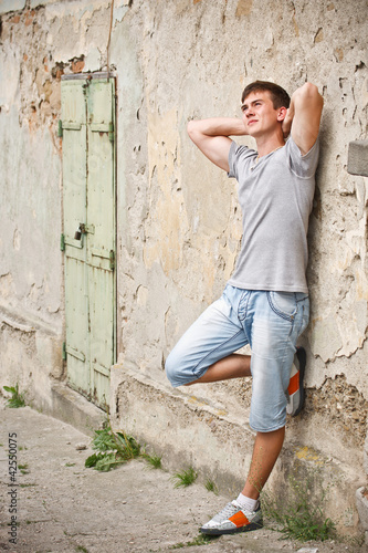 Young man leaning on a grunge wall