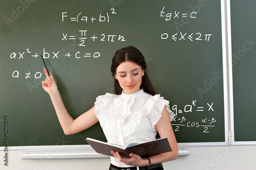 smiling teacher writes on blackboard
