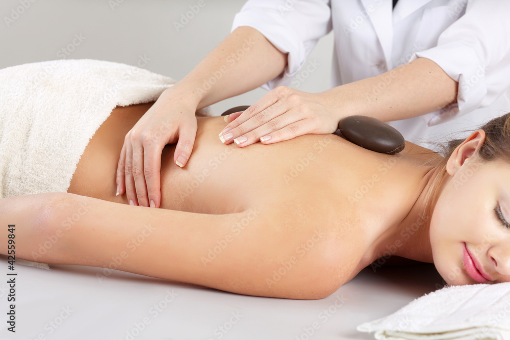 Obraz premium Girl on a stone therapy, hot stone massage. Isolated on white.
