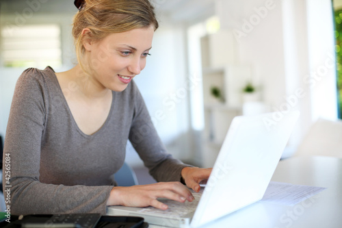 Beautiful young woman studying at home on laptop