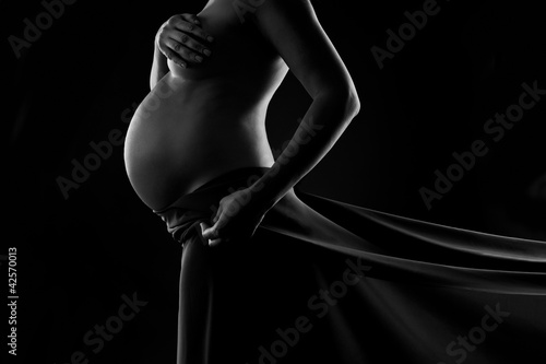 Pregnant woman in silk veil demonstrating her belly