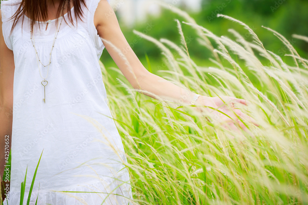 Fototapeta premium Woman's hand touching green grass
