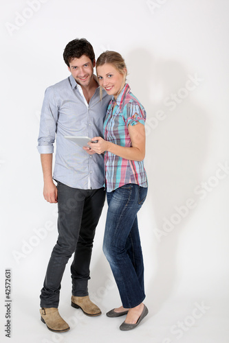 Young couple on white background holding digital tablet