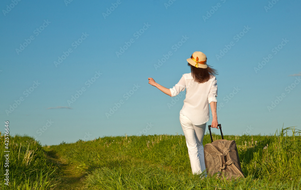 Beautiful traveller walking along the road with a suitcase Beautiful traveller walking along the road with a suitcase