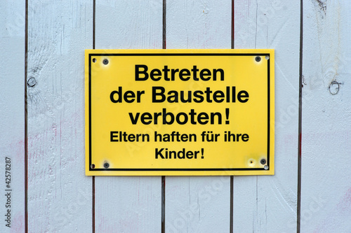 Betreten der Baustelle verboten! gelbes Schild Hinweis an Bretterwand