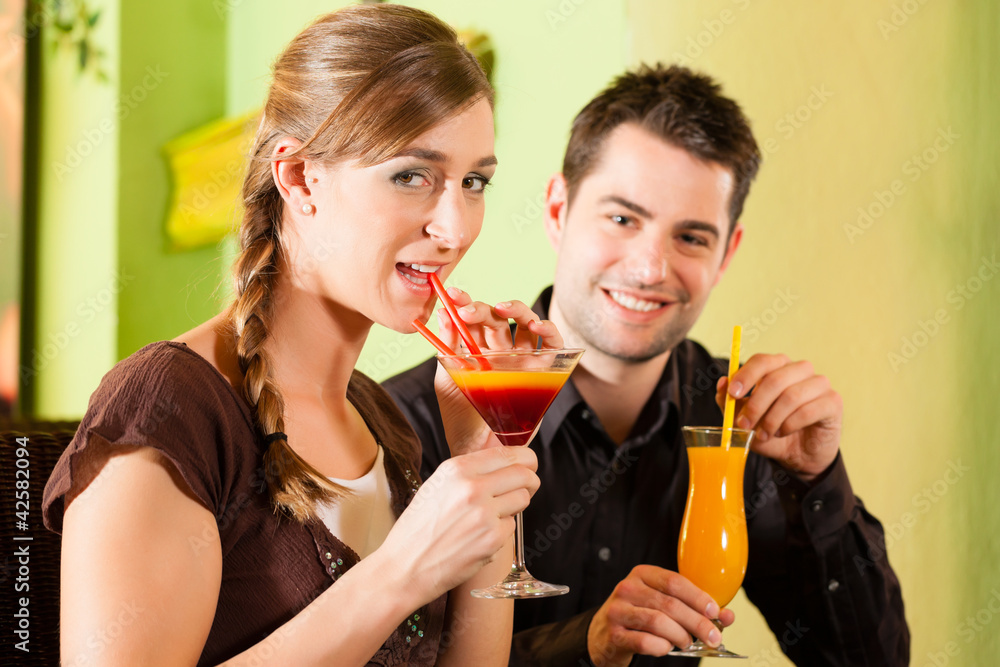 Young couple drinking cocktails in bar or restaurant