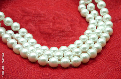 Pearl necklace on red background