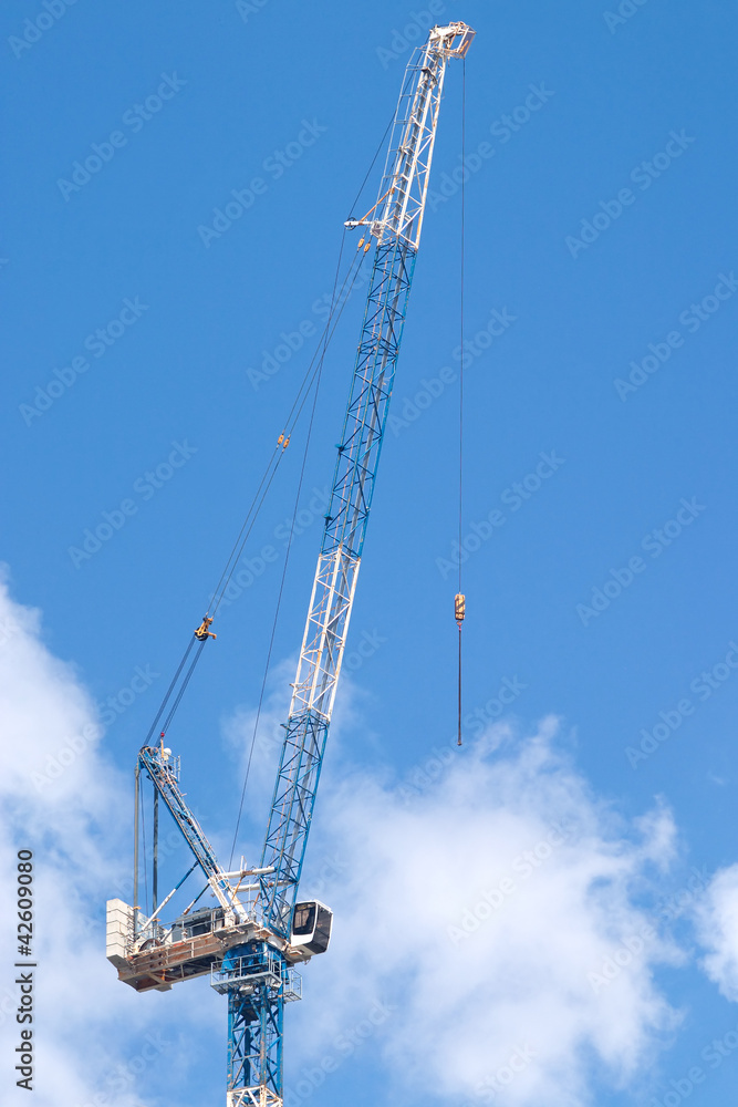 Hoisting tower crane in blue sky with clouds