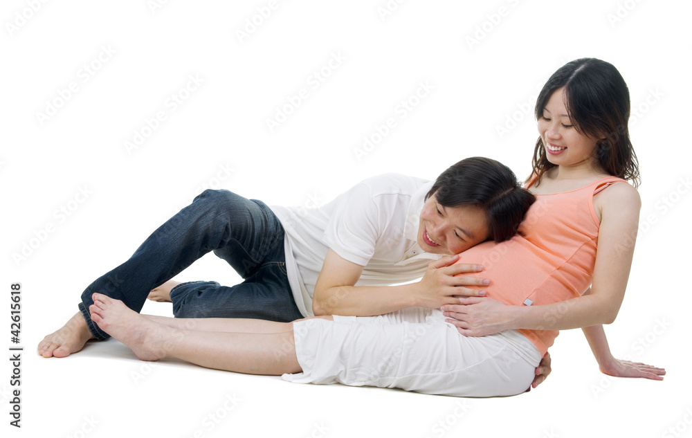 Asian man listening to pregnant wife's belly