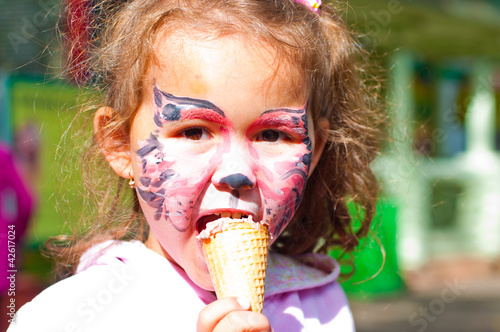 девочка с рисунком на лице ест мороженое