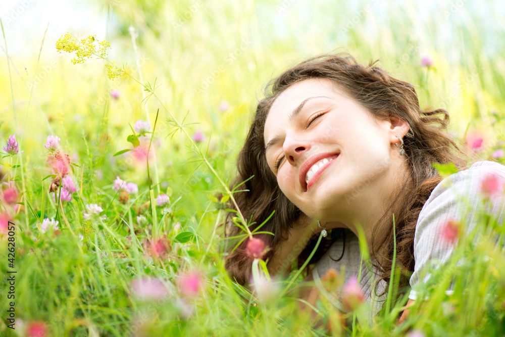 Beautiful Young Woman lying in Meadow of Flowers. Enjoy Nature Beautiful Young Woman lying in Meadow of Flowers. Enjoy Nature