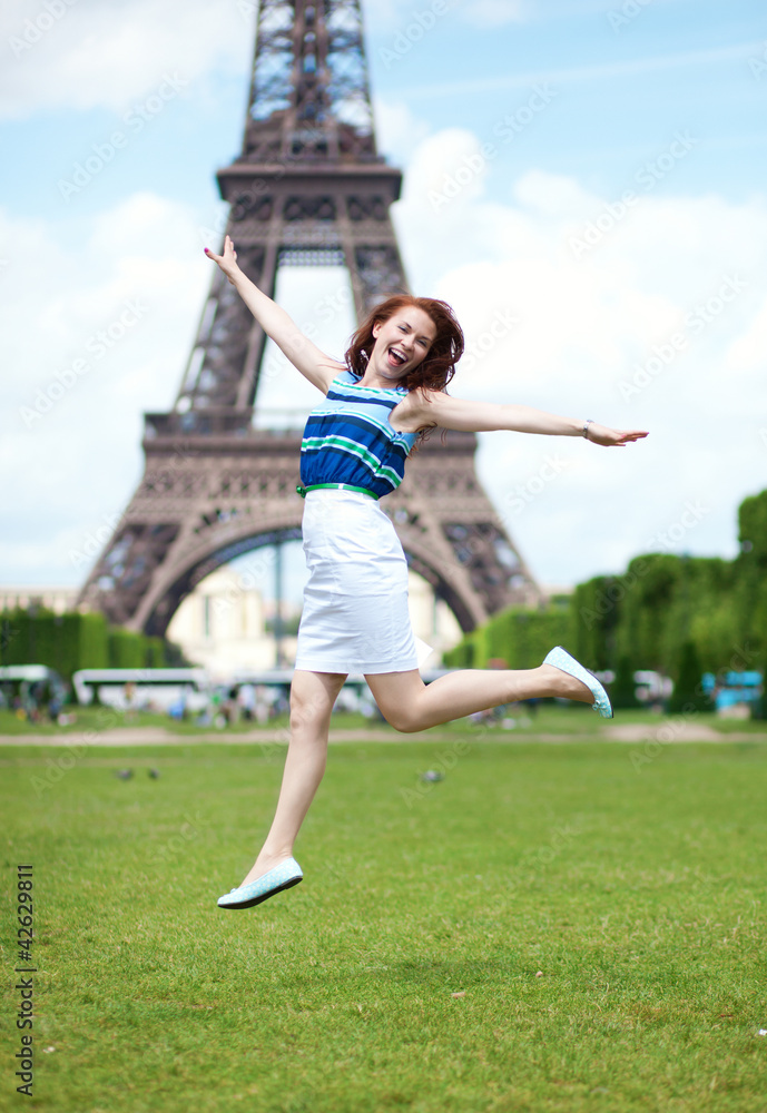 Happy beautiful girl jumping near the Eiffel Tower in Paris
