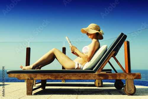 Attractive woman sunbathing while reading a magazine photo