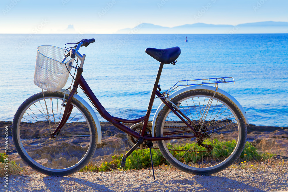Bicycle in formentera beach with Ibiza sunset