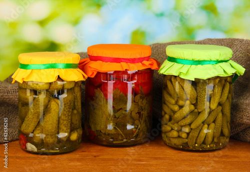 Jars with canned vegetables on green background close-up