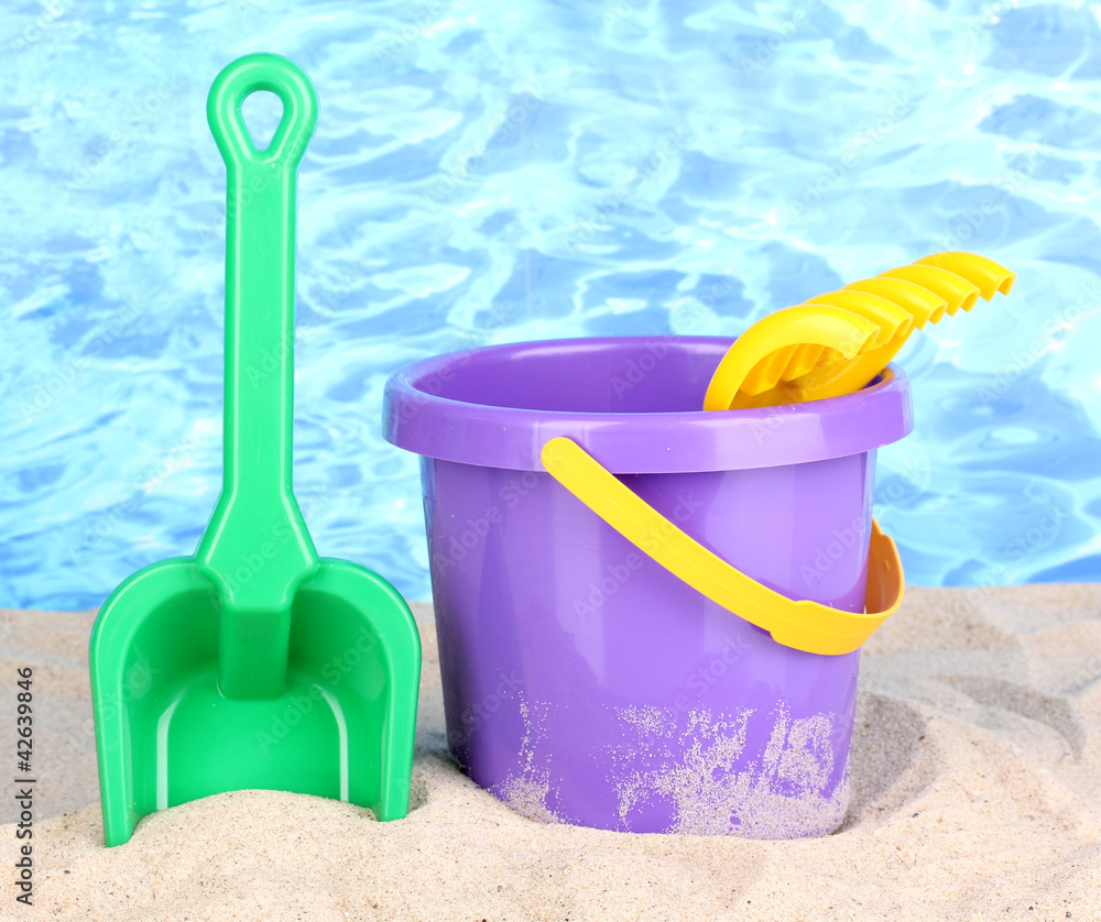 Children's beach toys on sand on water background Children's beach toys on sand on water background