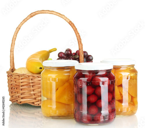 Jars of canned fruit and basket with fruit isolated on white