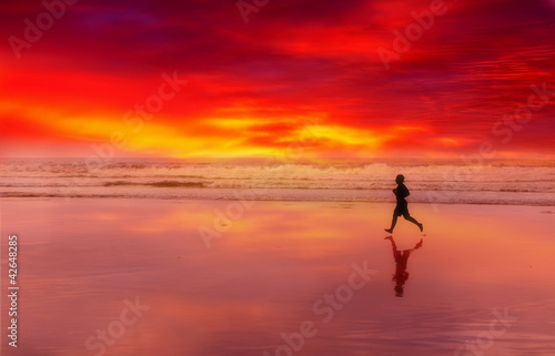 Silhouette of the person running on a sunset on an ocean coast