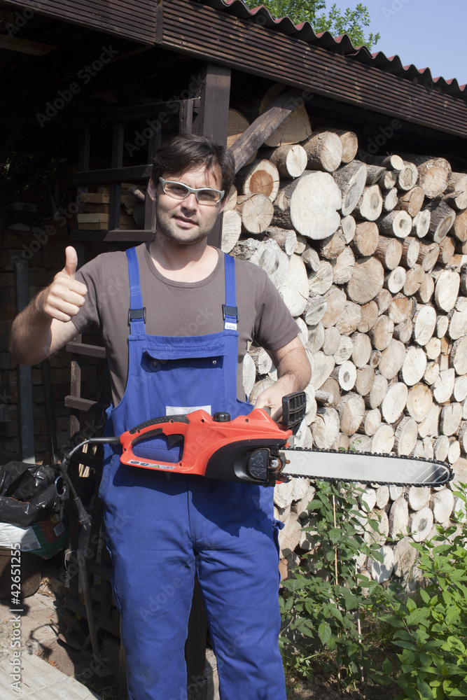 Mann mit Motorsäge und mit erhobenem Daumen Mann mit Motorsäge und mit erhobenem Daumen