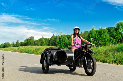 Pretty woman riding a motorcycle with a sidecar.
