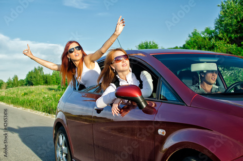 Two pretty happy girls in the car. Concept of carefree roadtrip © M-Production