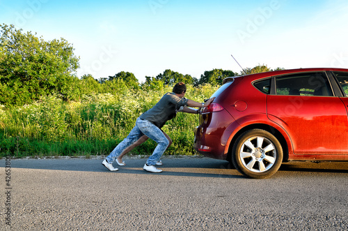 Man and woman pushing a broken car