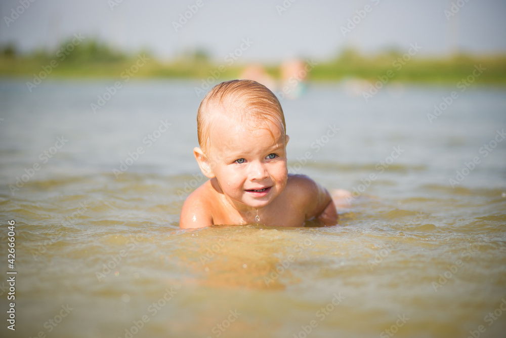 Adorable baby splashing water on lake beach Adorable baby splashing water on lake beach