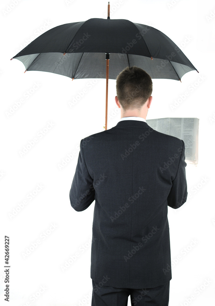 Businessman with an umbrella reading a newspaper Businessman with an umbrella reading a newspaper