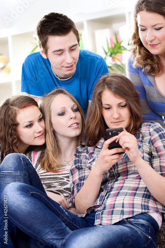Group of teenagers reading interesting sms