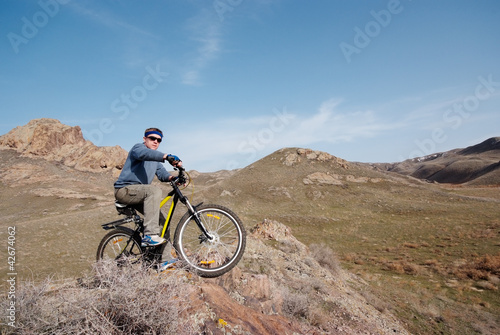 Bicyclist in mountain terrain overcomes obstacle