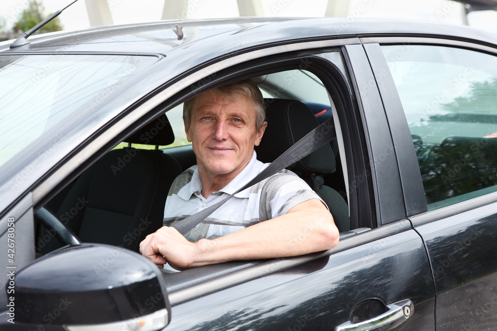 Smiling senior driver in own car with seat belt