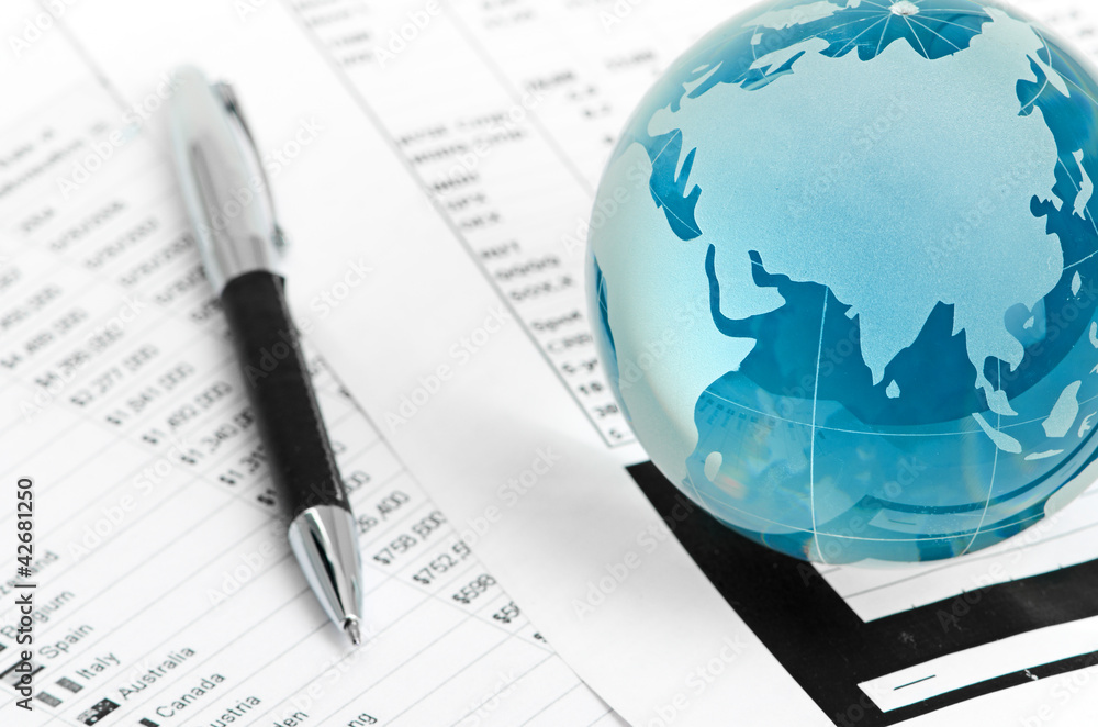 Glass globe and pen on finance chart Glass globe and pen on finance chart