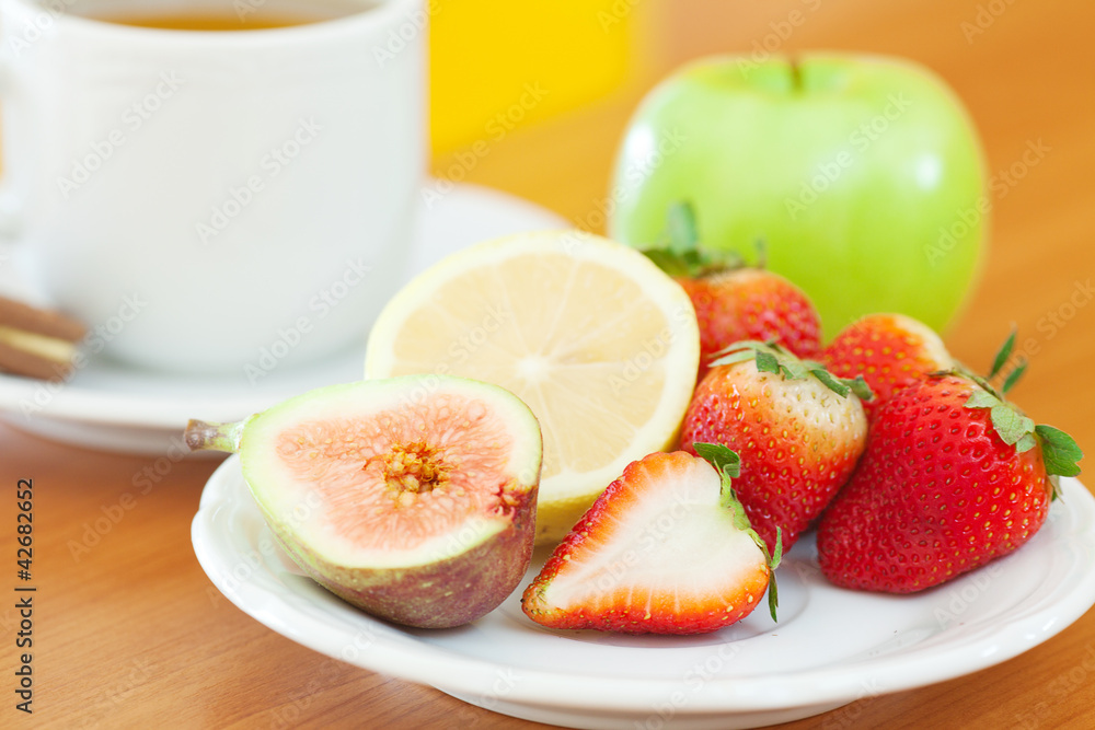 cup of tea,cookie,apple, lemon, fig and strawberries on a plate cup of tea,cookie,apple, lemon, fig and strawberries on a plate