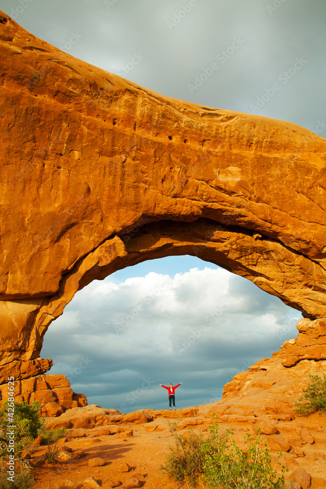 Woman staying with raised hands inside an Arch