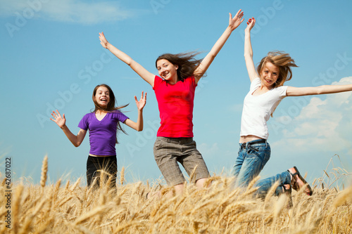 Teen girls jumping at a wheat field