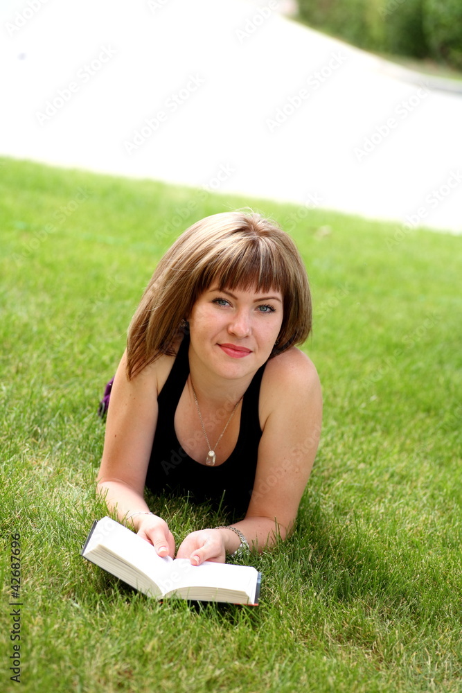 Young happy woman looking at the camera while reading a book Young happy woman looking at the camera while reading a book