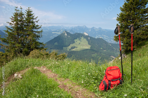 Bild auf Leinwand Roter Rucksack und Wanderstöcke in den bayerischen Alpen.