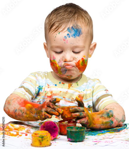 Little boy is playing with paints