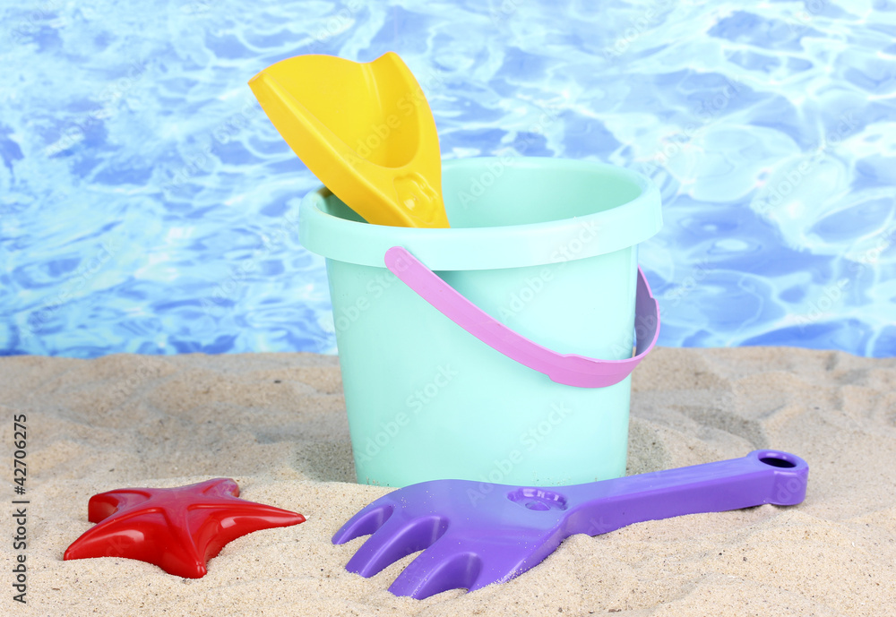 Children's beach toys on sand on water background Children's beach toys on sand on water background