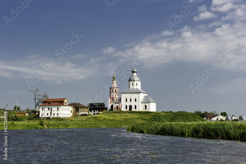 Белая русская церковь на берегу реки.