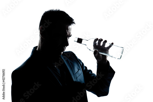 silhouette man drunk looking at an empty alcohol botlle