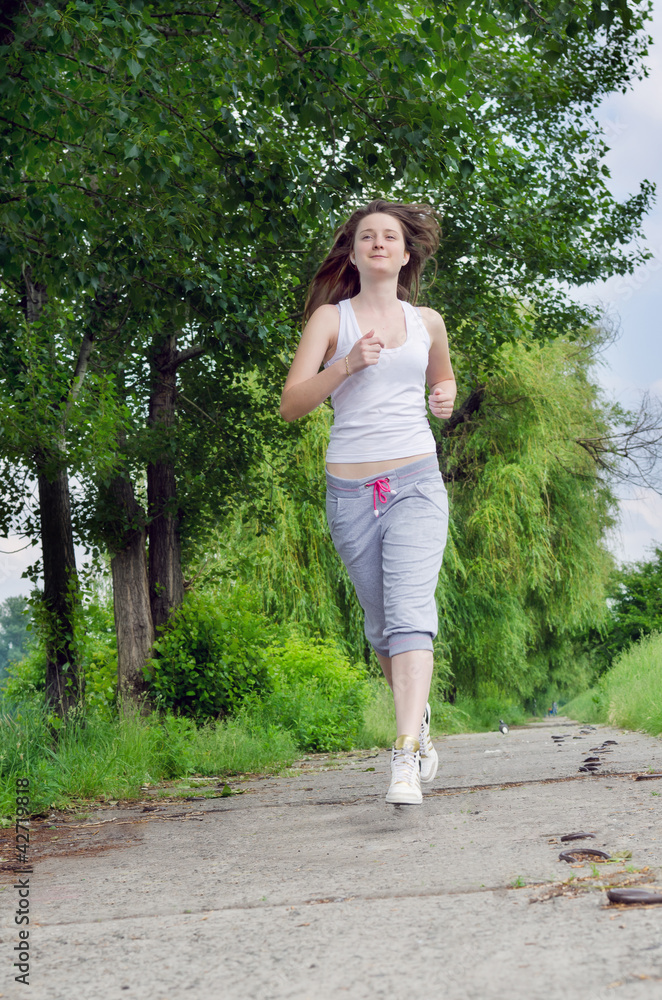 Young woman jogging through a park Young woman jogging through a park