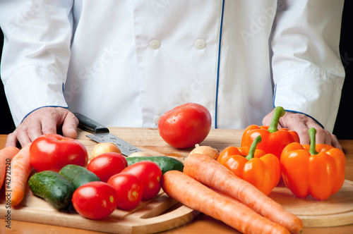 Chef standing by the table with variety of fresh vegetables
